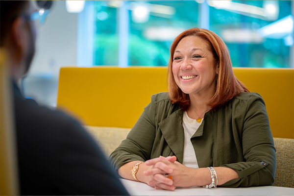Synchrony woman employee sitting at table smiling with another employee